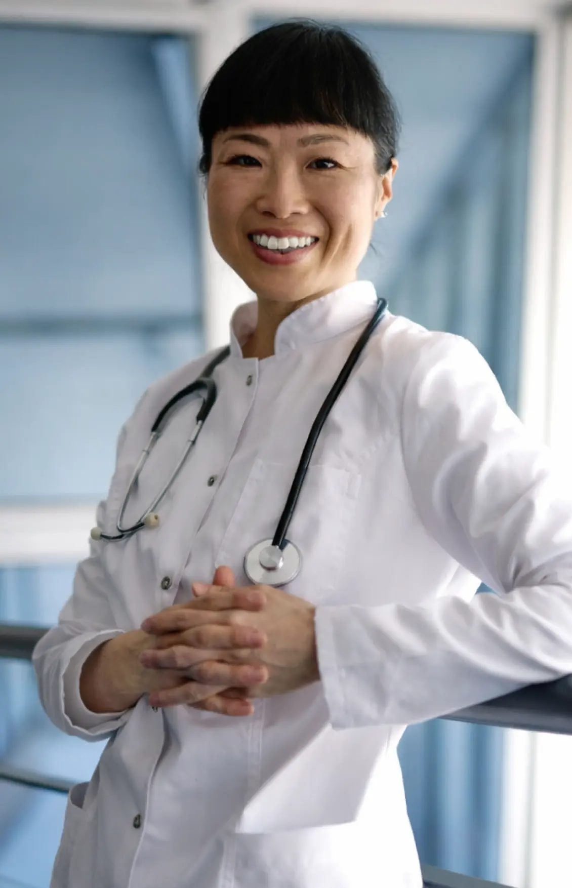 Smiling nurse leaning against railing.