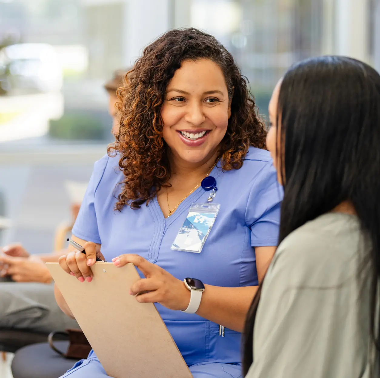 Nurse in scrubs talking with patient.
